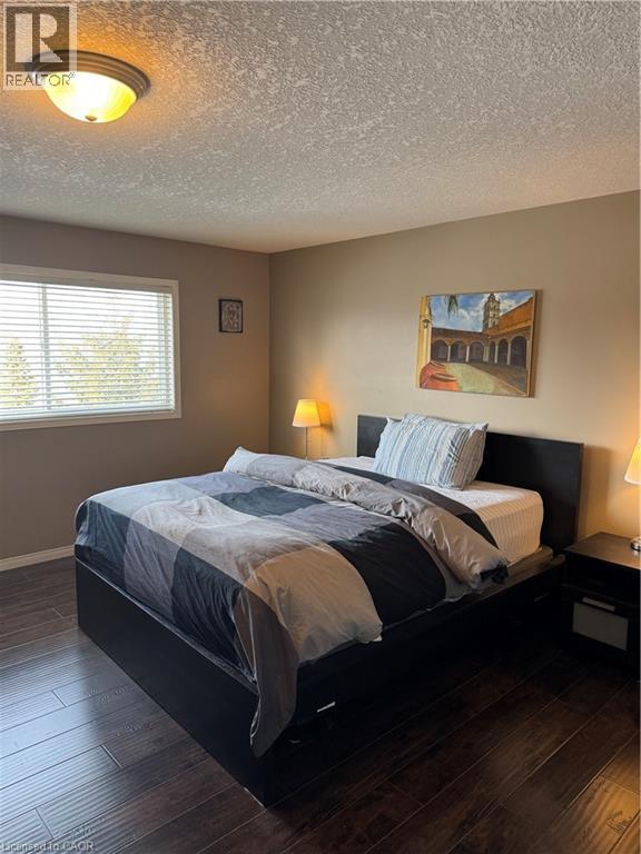 A bedroom with a bed, two lamps, and a painting on the wall.