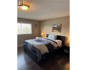 A bedroom with a bed, two lamps, and a painting on the wall.