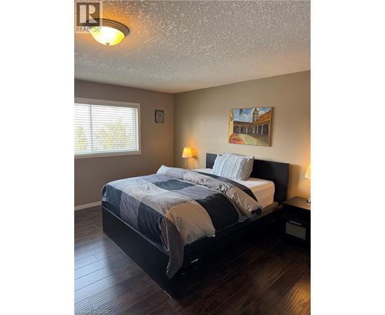 A bedroom with a bed, two lamps, and a painting on the wall.