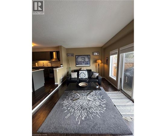 A living room with a grey rug and a black and white couch.