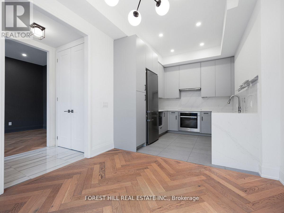 A modern kitchen with white cabinets and a wooden floor.