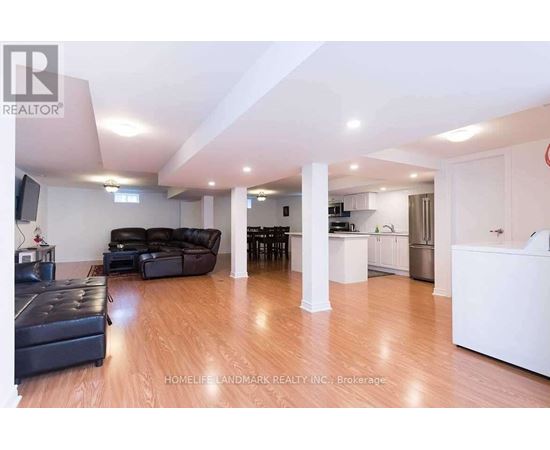 A living room with a black leather couch and a wooden floor.