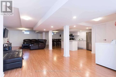A living room with a black leather couch and a wooden floor.