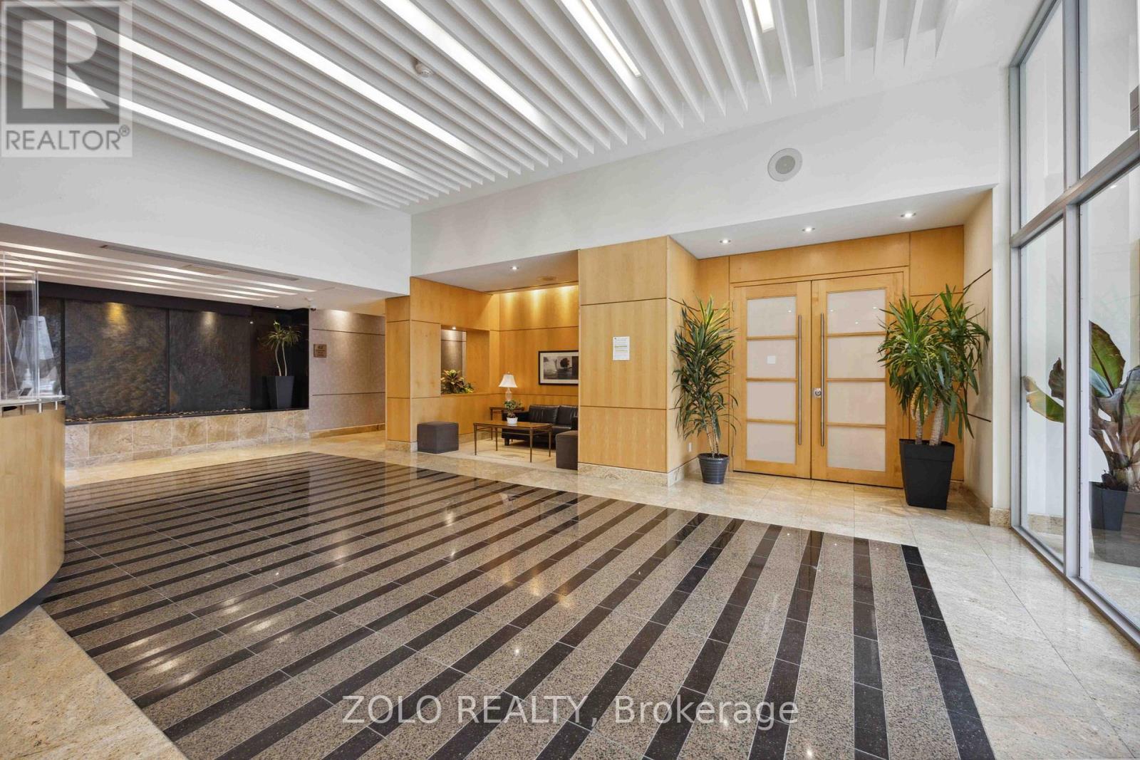 A spacious office lobby with a reception desk and a striped carpet.