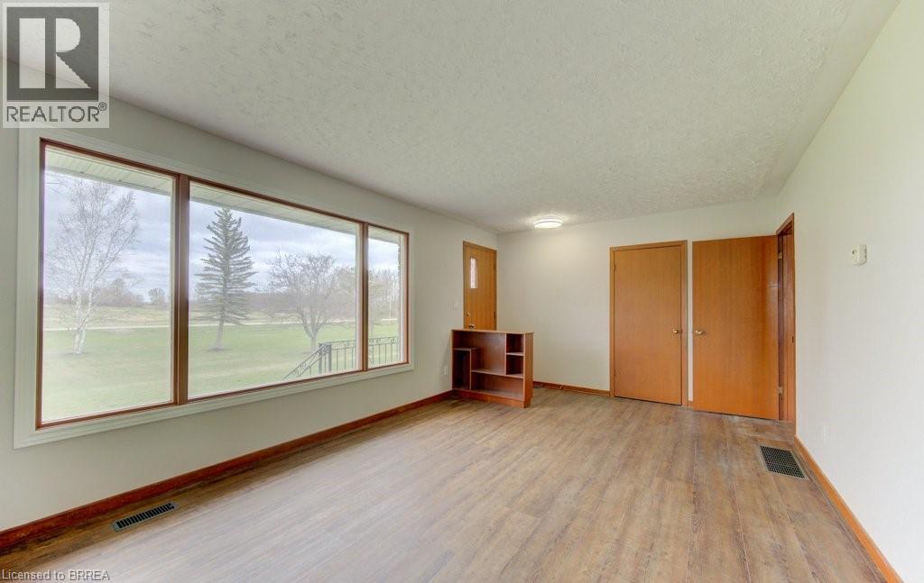 A room with wooden floors and a large window overlooking a grassy area.