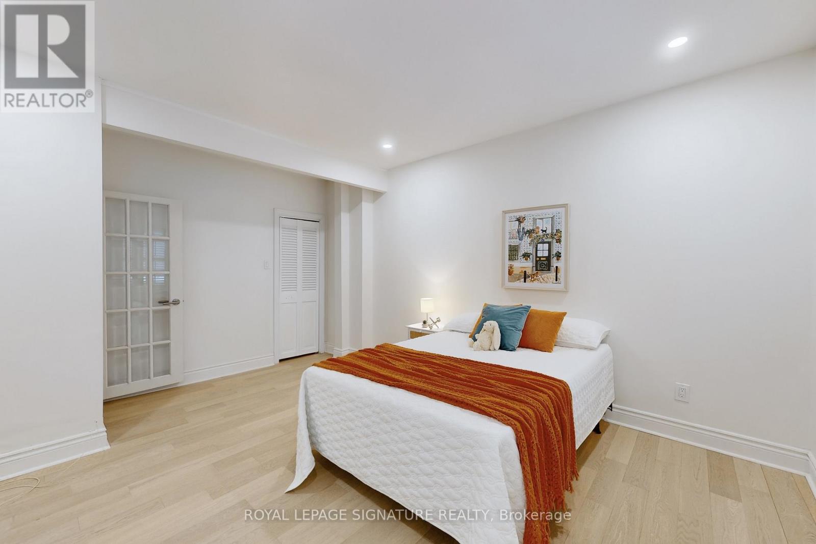 A bedroom with a white bed and a picture on the wall.