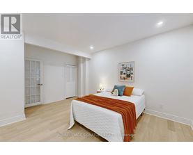A bedroom with a white bed and a picture on the wall.