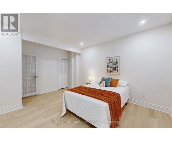 A bedroom with a white bed and a picture on the wall.