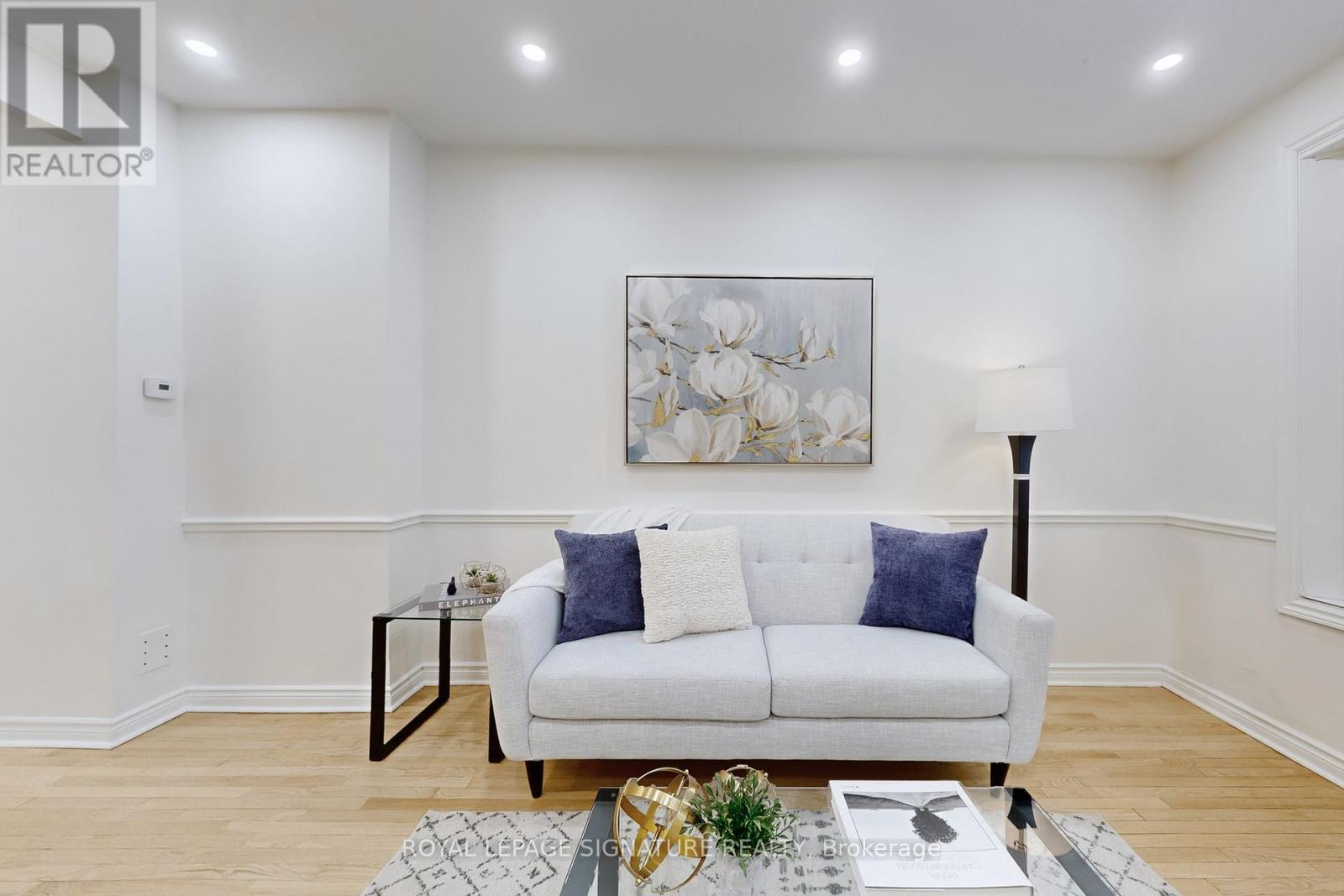 A living room with a white couch and a painting on the wall.