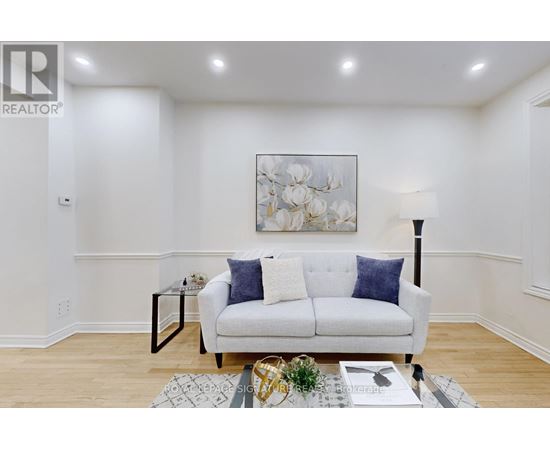 A living room with a white couch and a painting on the wall.