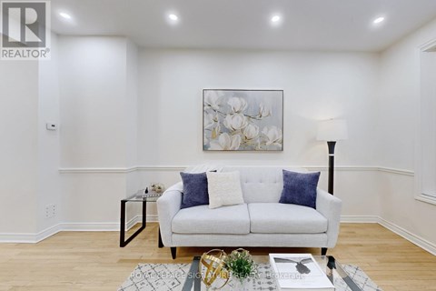 A living room with a white couch and a painting on the wall.