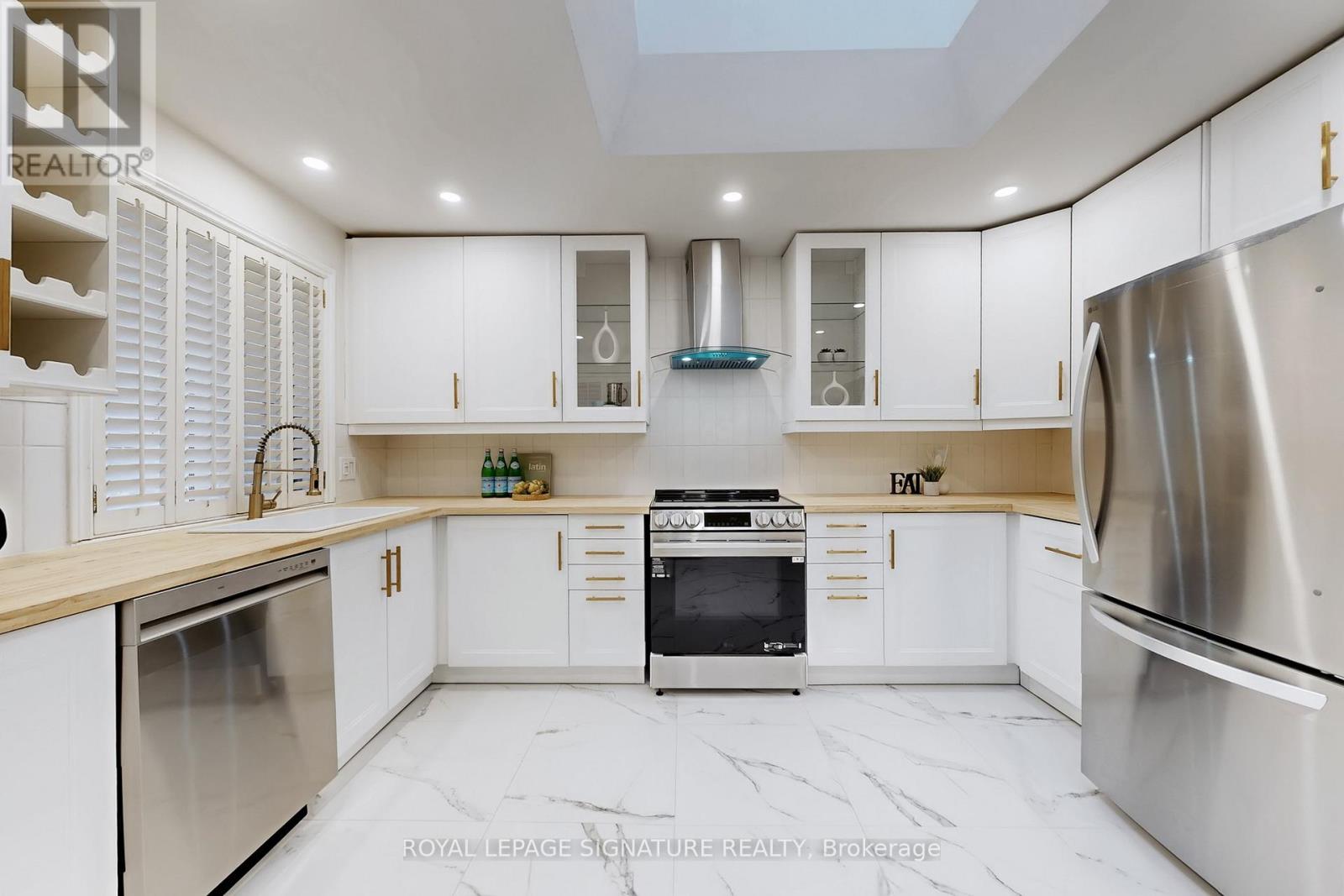 A modern kitchen with white cabinets and stainless steel appliances.