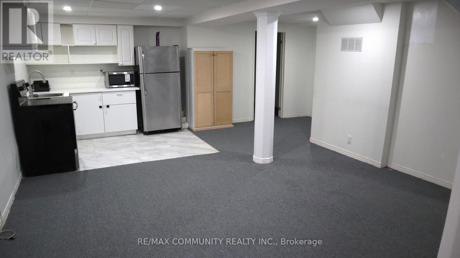 A kitchen area with a refrigerator, toaster, and cabinets.