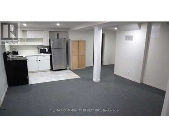 A kitchen area with a refrigerator, toaster, and cabinets.