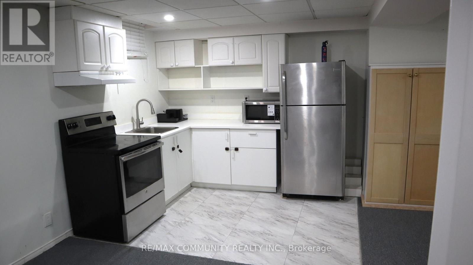 A kitchen with a refrigerator, oven, and microwave.