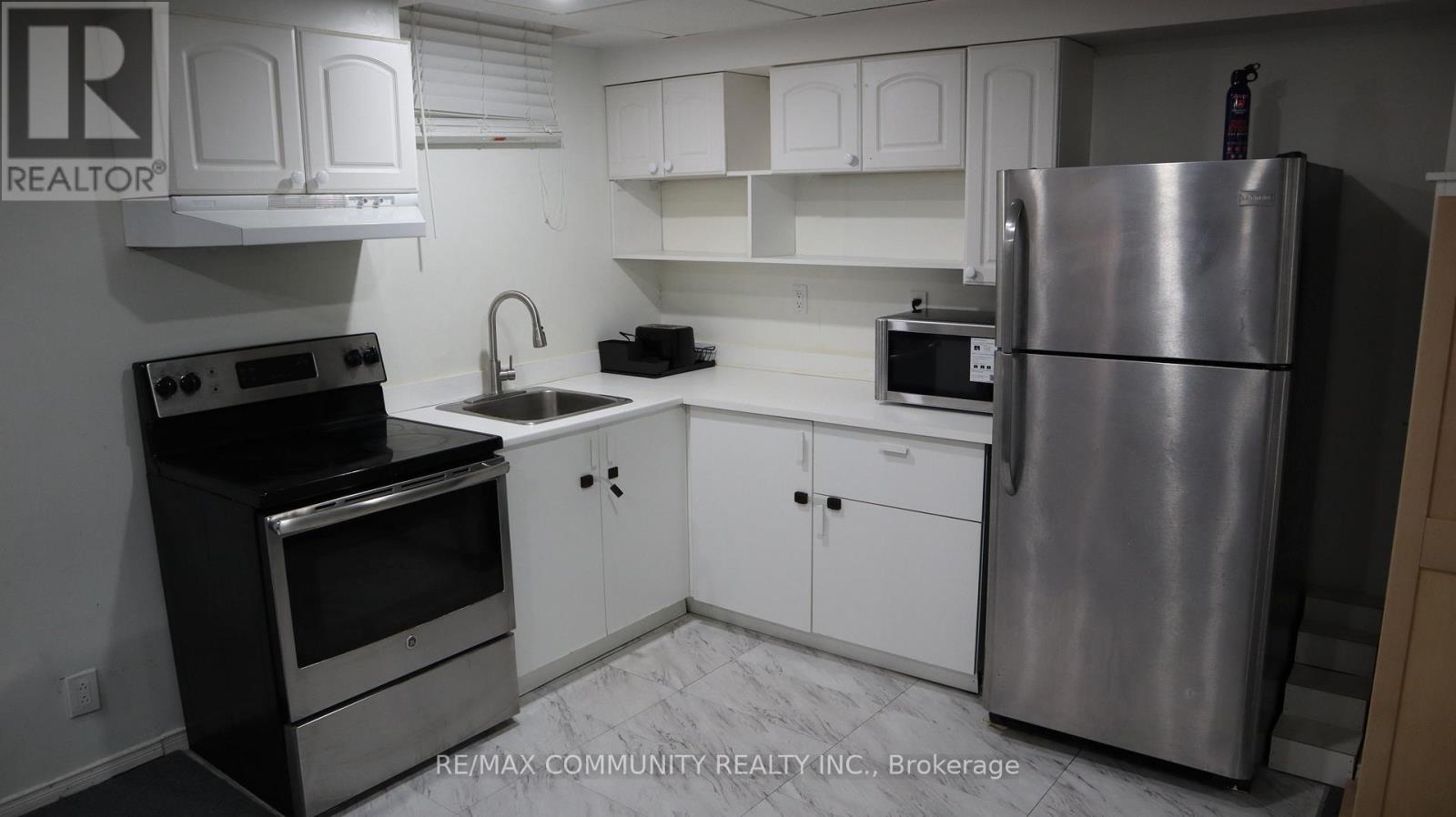 A kitchen with white cabinets and a stainless steel refrigerator.