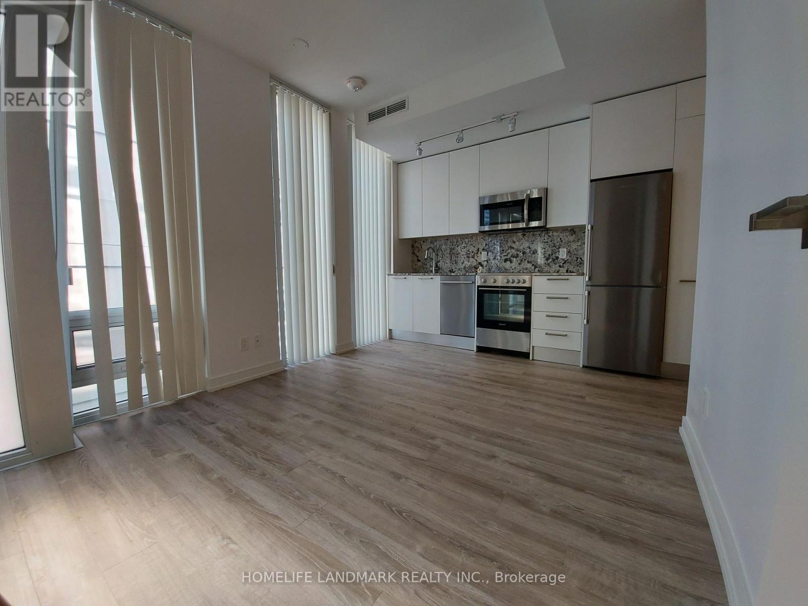 A spacious kitchen with wooden floors and white cabinets.