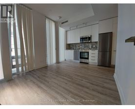 A spacious kitchen with wooden floors and white cabinets.