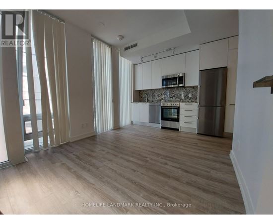 A spacious kitchen with wooden floors and white cabinets.