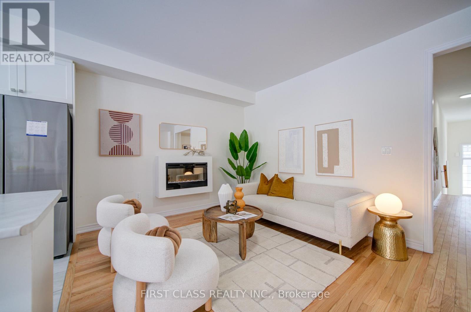 A modern living room with a white sofa, a fireplace, and a wooden floor.