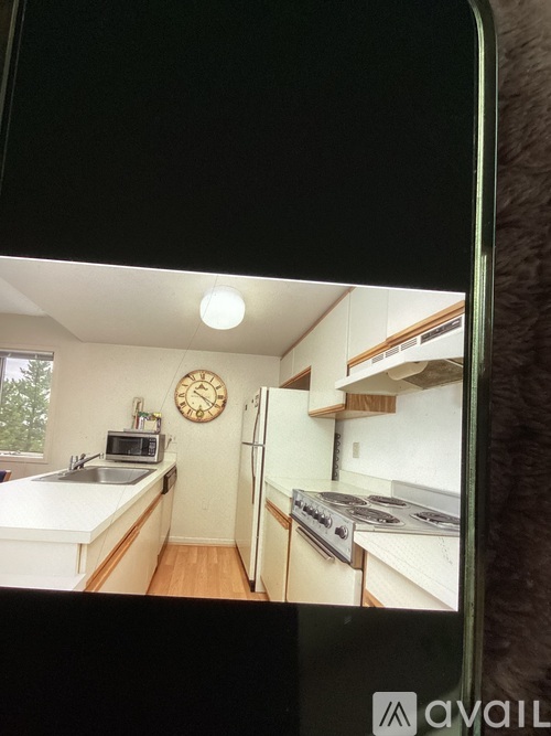 A kitchen with a clock on the wall and a stove top oven.
