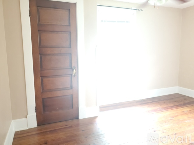 A wooden door is in a room with a white wall and wooden floor.
