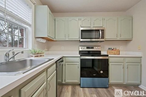 A kitchen with a sink, stove, and microwave.