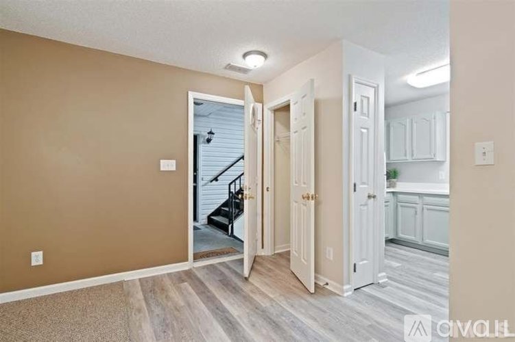 A room with beige walls and a carpeted floor leading to a staircase.