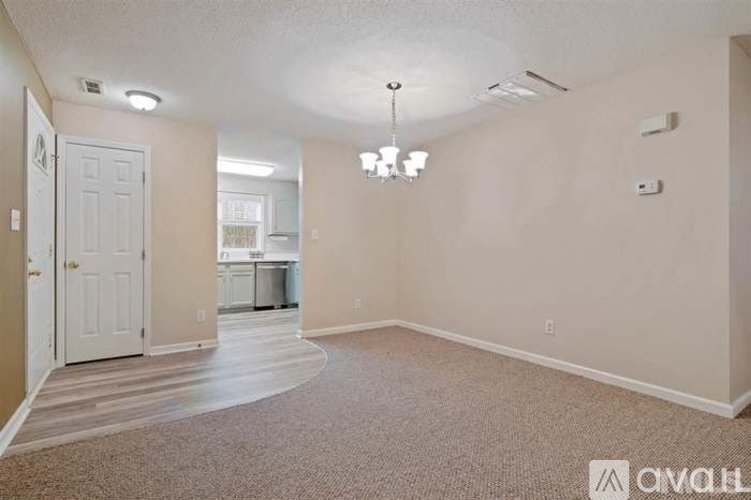 A spacious room with a carpeted floor and a chandelier hanging from the ceiling.