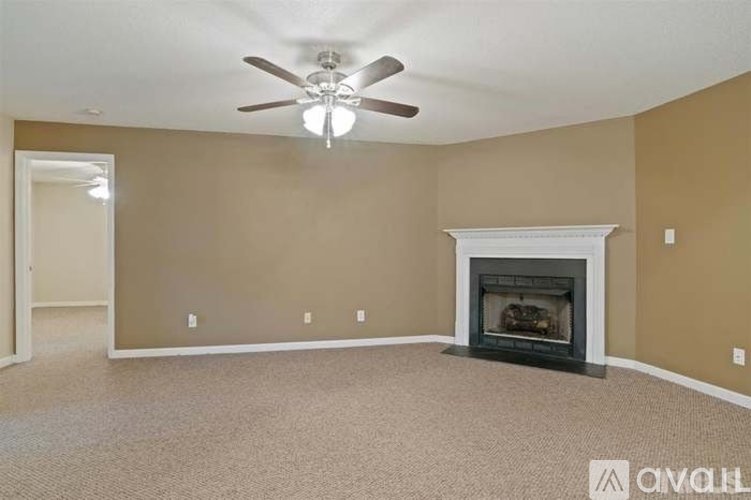 A living room with a fireplace and a ceiling fan.