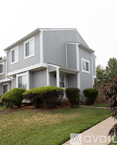 A grey house with a white trim and a small front yard.