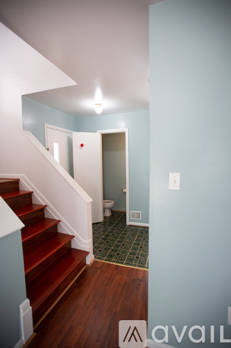 A hallway with a staircase and a bathroom.