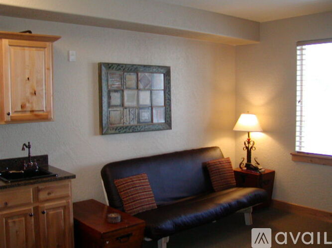 A living room with a brown leather couch and a wooden cabinet.