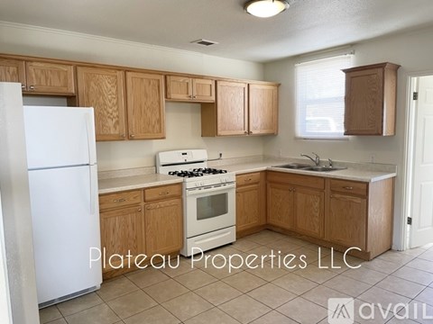 A kitchen with wooden cabinets and a white fridge is for sale.