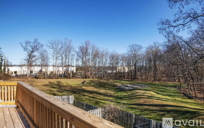 A wooden deck overlooks a grassy field with trees in the distance.