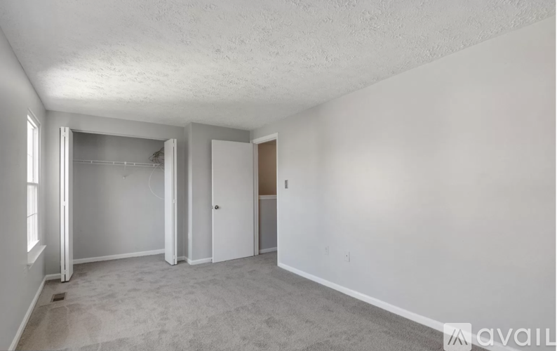 A spacious room with a carpeted floor and white walls.
