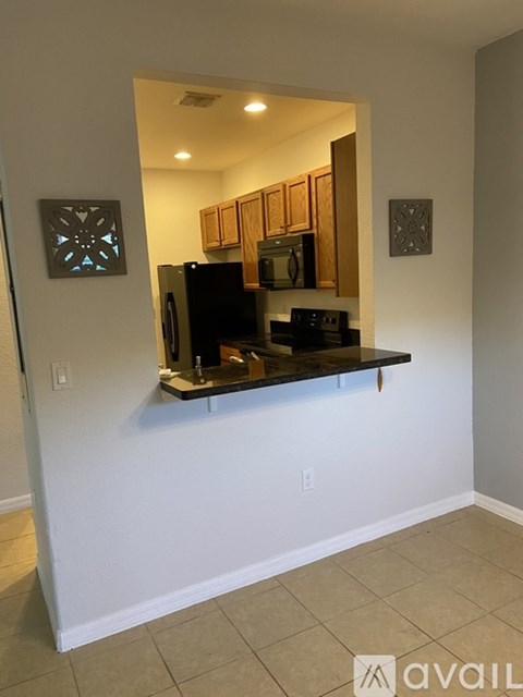 A kitchen area with a counter and cabinets is visible through a window.