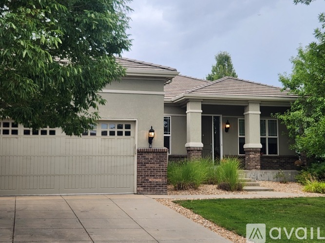 A house with a grey garage door and a brick pillar.