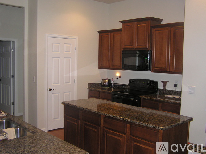 A kitchen with brown cabinets and a granite counter top.