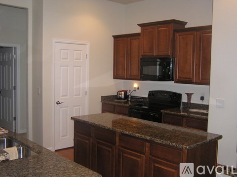 A kitchen with brown cabinets and a granite counter top.