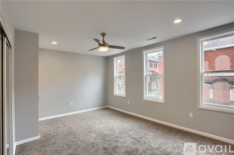 A spacious room with a ceiling fan and carpeted floor.
