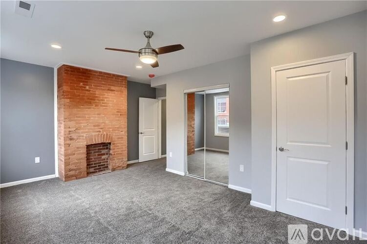 A room with a brick fireplace and a ceiling fan.