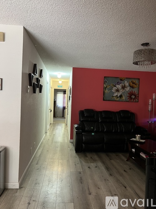 A long hallway with a black couch and a chandelier.