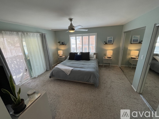 A bedroom with a bed, a ceiling fan, and two lamps.