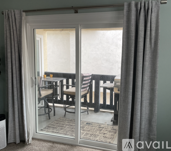 A dining room with a glass table and chairs is visible through a sliding door.