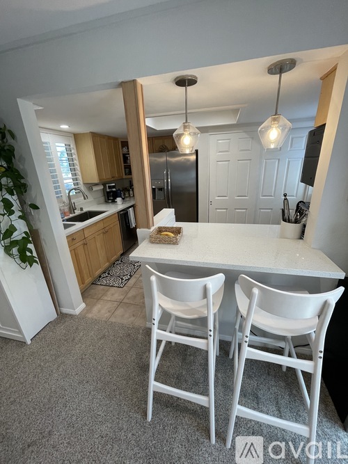 A kitchen with a table and chairs in the foreground and a refrigerator in the background.