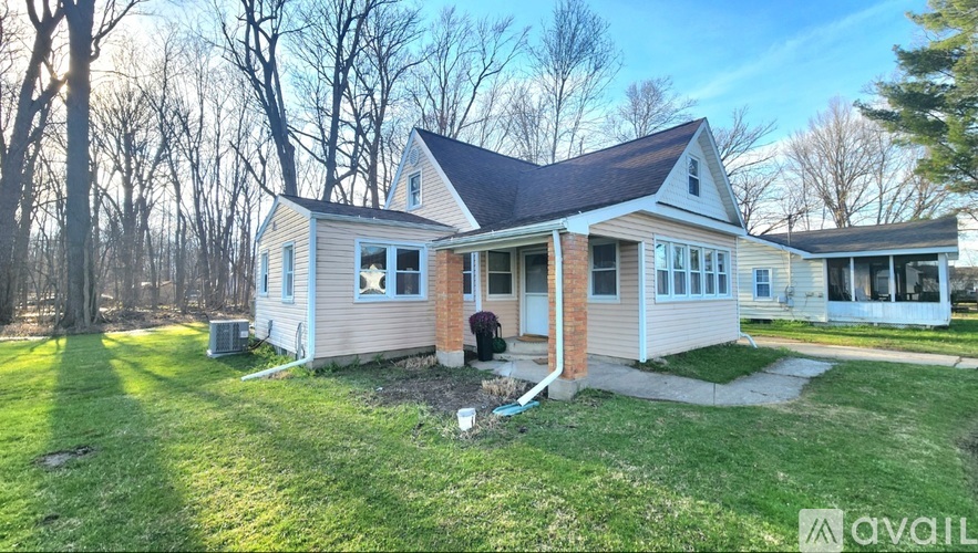 A house with a front yard and a tree in the background.