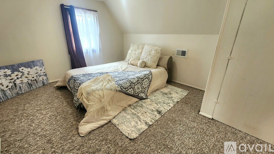 A bedroom with a bed, pillows, and a carpet.