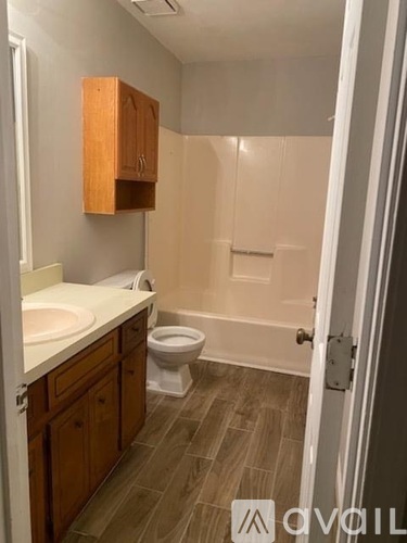 A bathroom with a toilet, sink, and wooden cabinets.
