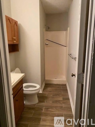 A bathroom with a toilet, sink, and wooden cabinets.